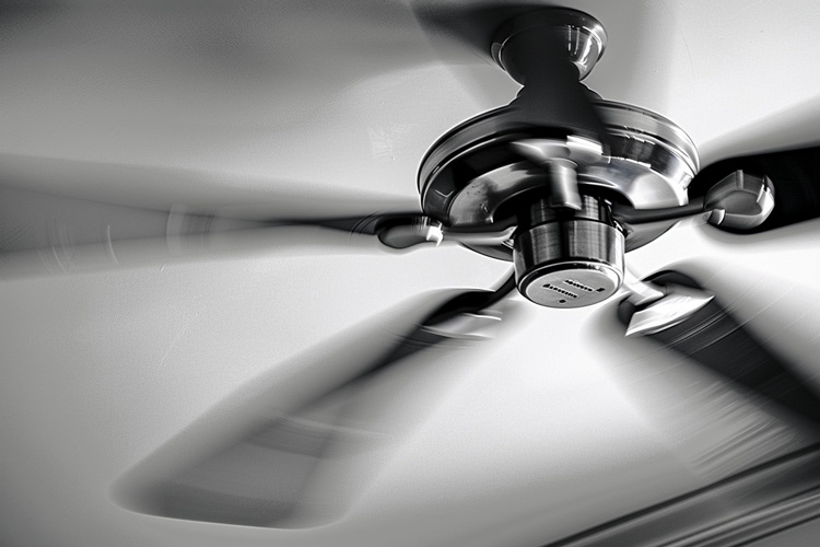 Ceiling fan spinning in a sunlit room, providing supplementary cooling.