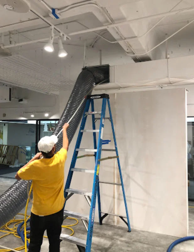 Atlanta Air Pro technician cleaning air ducts in a commercial space using specialized equipment.
