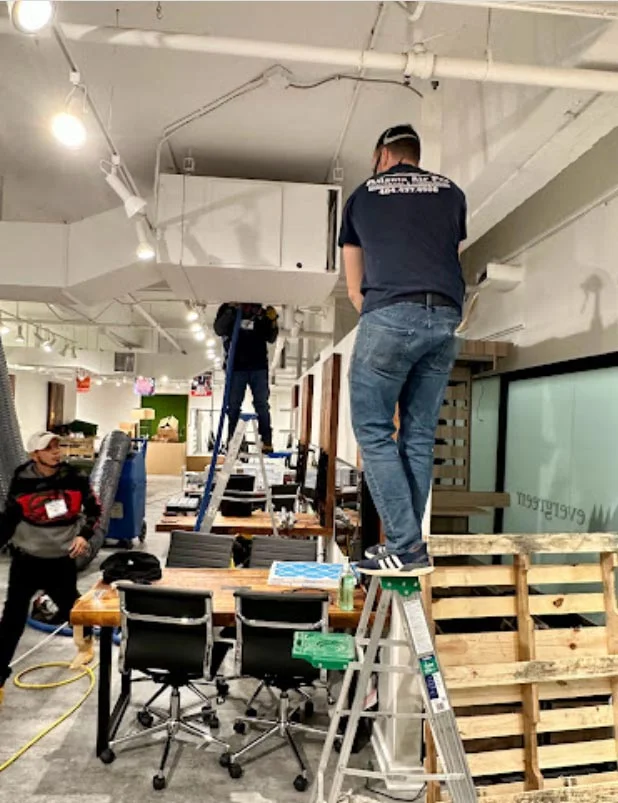 Atlanta Air Pro technicians performing air duct cleaning in a commercial office environment.