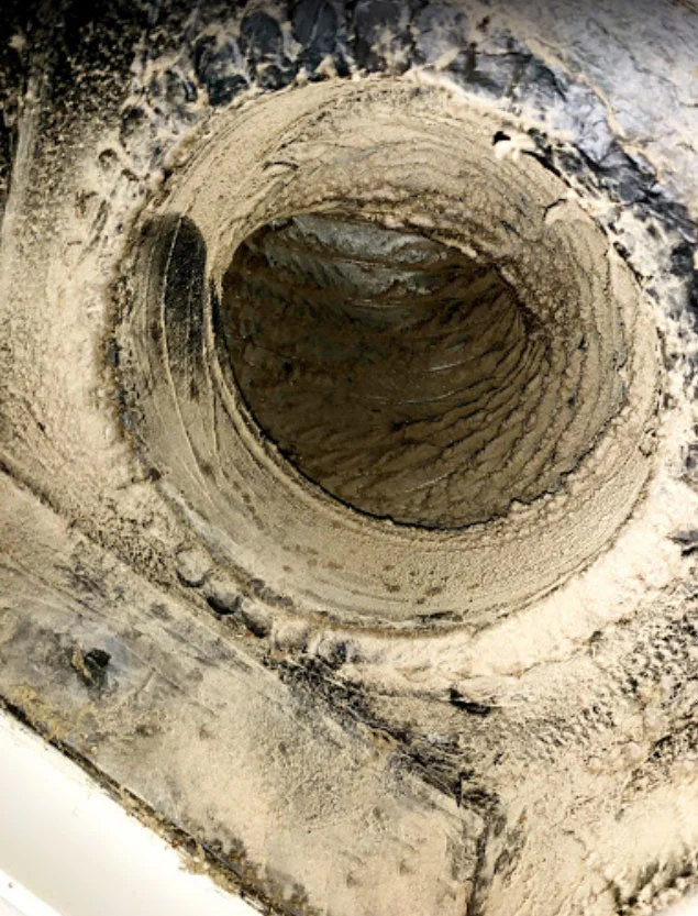 Heavily clogged air duct filled with dust and debris.