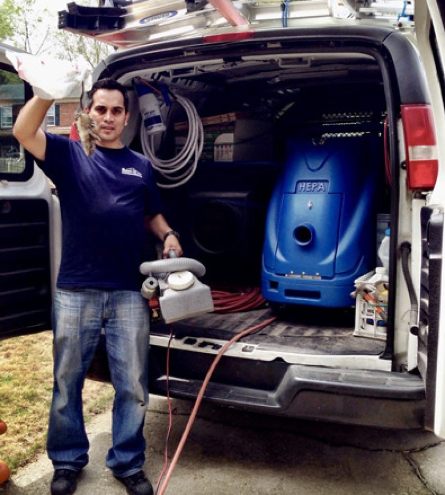 Air duct cleaning technician standing next to a service van equipped with cleaning equipment.